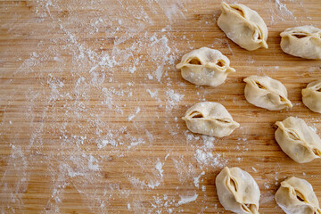 Homemade raw manty on a wooden board sprinkled with flour
