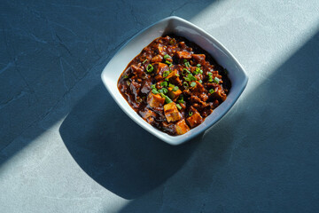 Mapo Tofu served in a bowl with a colorful garnish, mapo doufu, spicy tofu dish with minced meat, garlic, chili, and Sichuan pepper, chinese cuisine mapo tofu, soft tofu