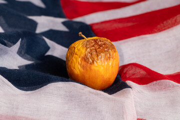 Rotten and dry apple lies on the American flag, crisis