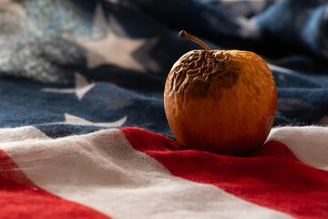 Rotten and dry apple lies on the American flag, crisis