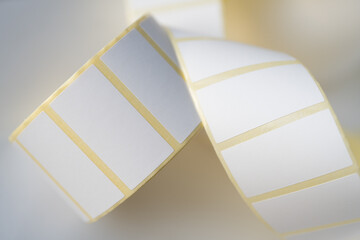 Close-up of a curled roll of blank self-adhesive labels with a yellow border, commonly used for...