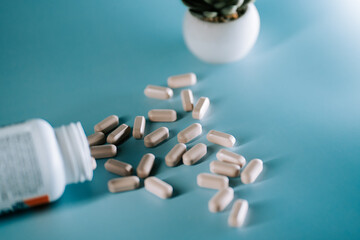 Capsules scattered on a blue surface with a small plant in the background during the day