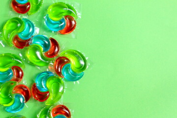 On a green juicy background there are many washing capsules with space for text.