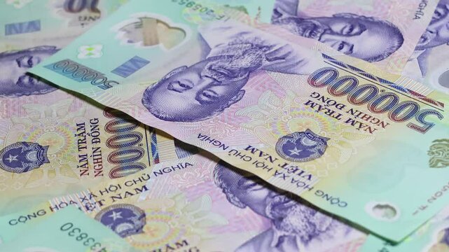 Vietnamese five hundred thousand dong (VND) banknotes are falling down on top of other notes. Real time motion video. Close up top angle view.
