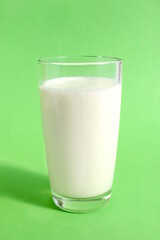  There is a glass of milk on a green background.