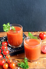 Two glasses of tomato juice are on the table.