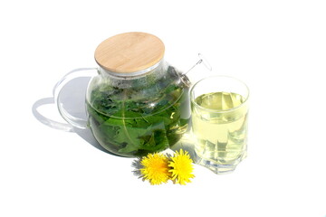 On a white background there is a glass transparent teapot with dandelion infusion.