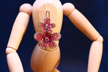 Wooden figurine toy with a gold pendant brooch flower