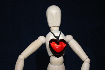 Figure of a wooden toy man with a precious stone in the form of a red heart