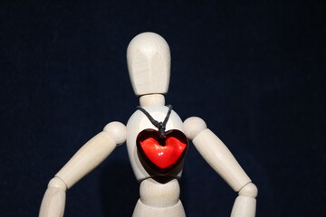 Figure of a wooden toy man with a precious stone in the form of a red heart