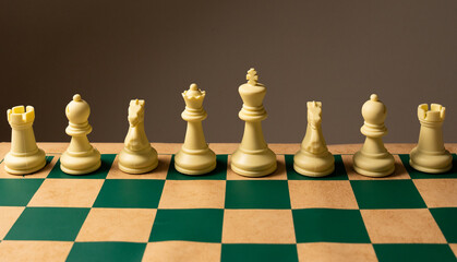 White chess pieces standing on green and beige chessboard