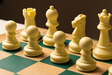 White chess pieces standing on green and beige chessboard