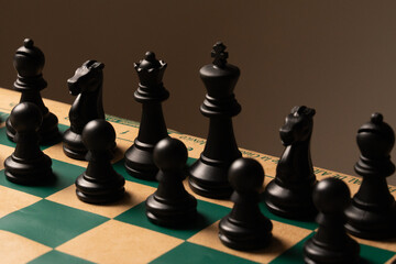 Black chess pieces standing on green and beige chessboard