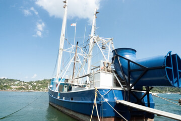 Industrial Fishing Vessel Docked in Coastal Town with Scenic Tropical Backdrop