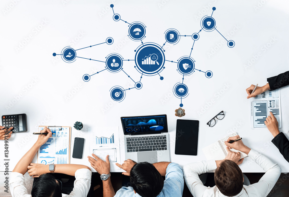 Fototapete A business management team engages in collaboration over digital strategy, analyzing charts and data on a table in a modern office environment for effective decision-making. Amity