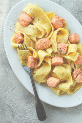 papardelle pasta, in creamy sauce with salmon, homemade, on a gray background, no people,