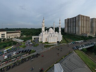  Masjid At Thohir Depok April 26, 2022 - The mosque is a beautiful white building with a large dome and several smaller domes. It is located in a residential area and is surrounded by trees