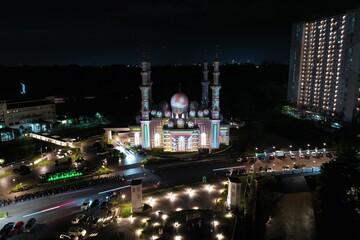 Fototapeta na wymiar Masjid At Thohir Depok April 26, 2022 - The mosque is a beautiful white building with a large dome and several smaller domes. It is located in a residential area and is surrounded by trees