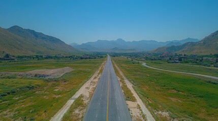 Scenic road leading to distant mountains under a serene blue sky view