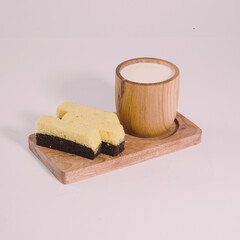 Steamed cheese brownies on a wooden tray with a glass of fresh milk
