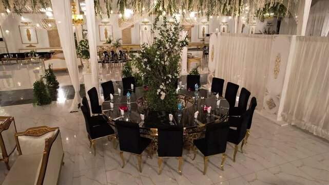 Elegant Banquet Hall with Luxurious Round Table Setup : A grand banquet hall featuring a lavish round table with black velvet chairs, floral centerpiece, and golden decor. Perfect for weddings, recept