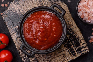 Red sauce or ketchup with salt and spices in ceramic sauce boat