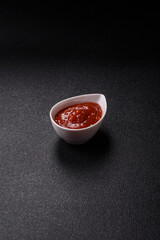 Red sauce or ketchup with salt and spices in ceramic sauce boat