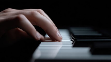 Fototapeta premium Close-up of hand playing piano keys. A hand gently touches piano keys in a dark studio