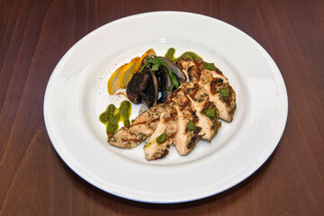 Chicken breast with Portobello mushrooms and chimichurri sauce on a wooden table