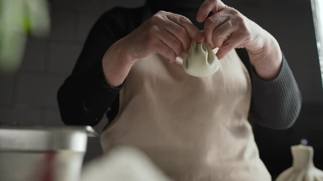 Skilled chef demonstrating khinkali preparation, deftly folding traditional georgian dumpling dough with precise culinary expertise in professional kitchen setting