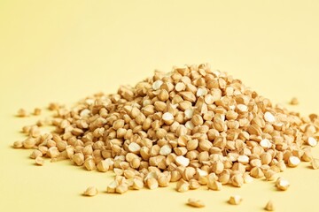 Fototapeta premium A pile of small beige food grains on a yellow surface