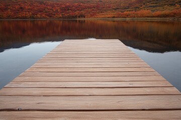 Fototapeta premium Wooden dock extends into tranquil lake, surrounded by autumn fol