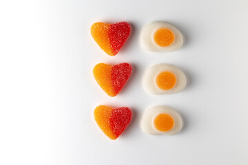 Heart and fried egg shaped candy creating a pattern on white background