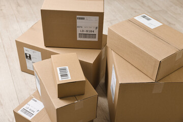 Cardboard parcel boxes with shipping labels on floor indoors, closeup