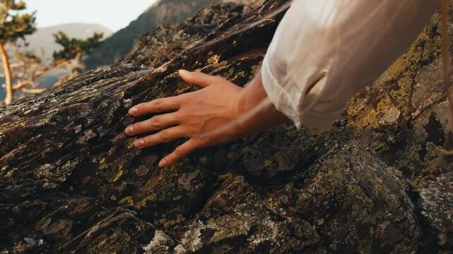 woman hand touching stone rock. hand close up. texture of ancient rocks mountains nature. traveler girl climbing rocks at sunset summer. panoramic view city capital Andorra la Vella. moss-grown stone