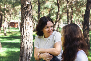 Fototapeta premium Two women engage in a deep conversation in a serene forest setting during daylight hours