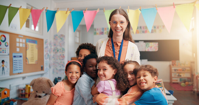 Happy, portrait and kids hugging teacher in classroom for bonding, learning and thank you. Love, children or students embracing woman educator for greeting in morning for lesson at elementary school.