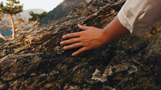 woman hand touching stone rock. hand close up. texture of ancient rocks mountains nature. traveler girl climbing rocks at sunset summer. panoramic view city capital Andorra la Vella. moss-grown stone