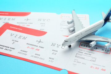 Travel agency. Flight tickets and plane model on light blue background, closeup
