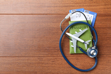 Medical tourism. Passport with tickets, stethoscope and airplane model on wooden background, top...