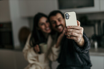 Happy couple taking a selfie in the kitchen while having breakfast