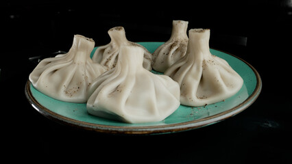 Khinkali georgian dumplings receiving freshly ground black pepper, enhancing culinary flavor with aromatic spice sprinkled by professional chef's skilled hand