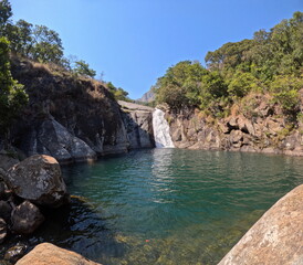 Waterfall in mountains surrounded by trees with blue water