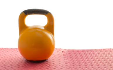 Old heavy yellow kettlebell on the gym floor with weights. Fitness training and healthy lifestyle concept. Possible place for text or writing on the kettlebell. Cut out, on isolated white background.