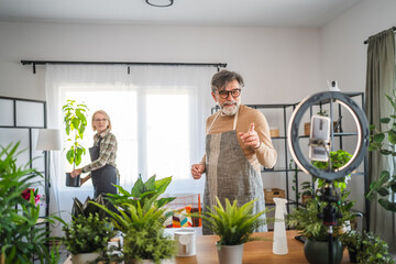 mature couple use cellphone for live streaming and presenting home plants