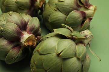 Obraz premium Fresh artichoke on green background. Whole green artichokes mockup. Close-up.