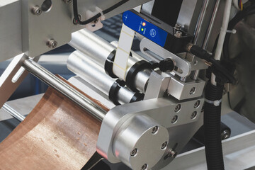 Fragment of the conveyor of sticking labeling machine for packaging food products or pharmaceuticals. Abstract industrial background.