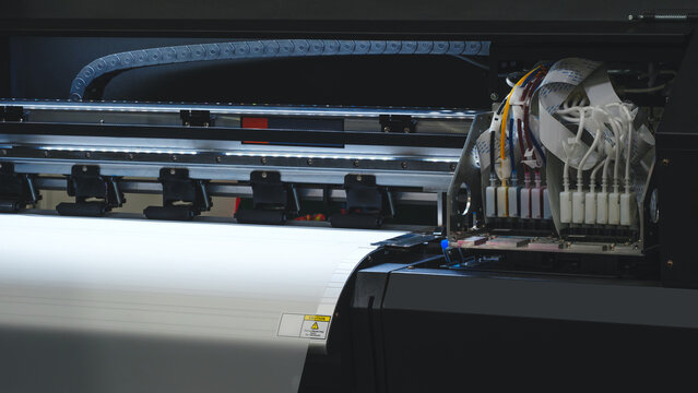 A printer is open and has a white sheet of paper inside. The printer is black and has a yellow and red color