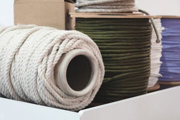 A white and green rope is placed on top of a white box. The white rope is wrapped around the green rope, creating a visually appealing and colorful display