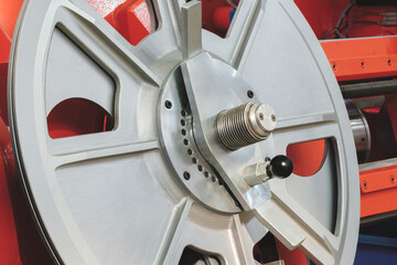 A silver wheel with a black handle is on a red background. The wheel is in the center of the image and is surrounded by a red frame